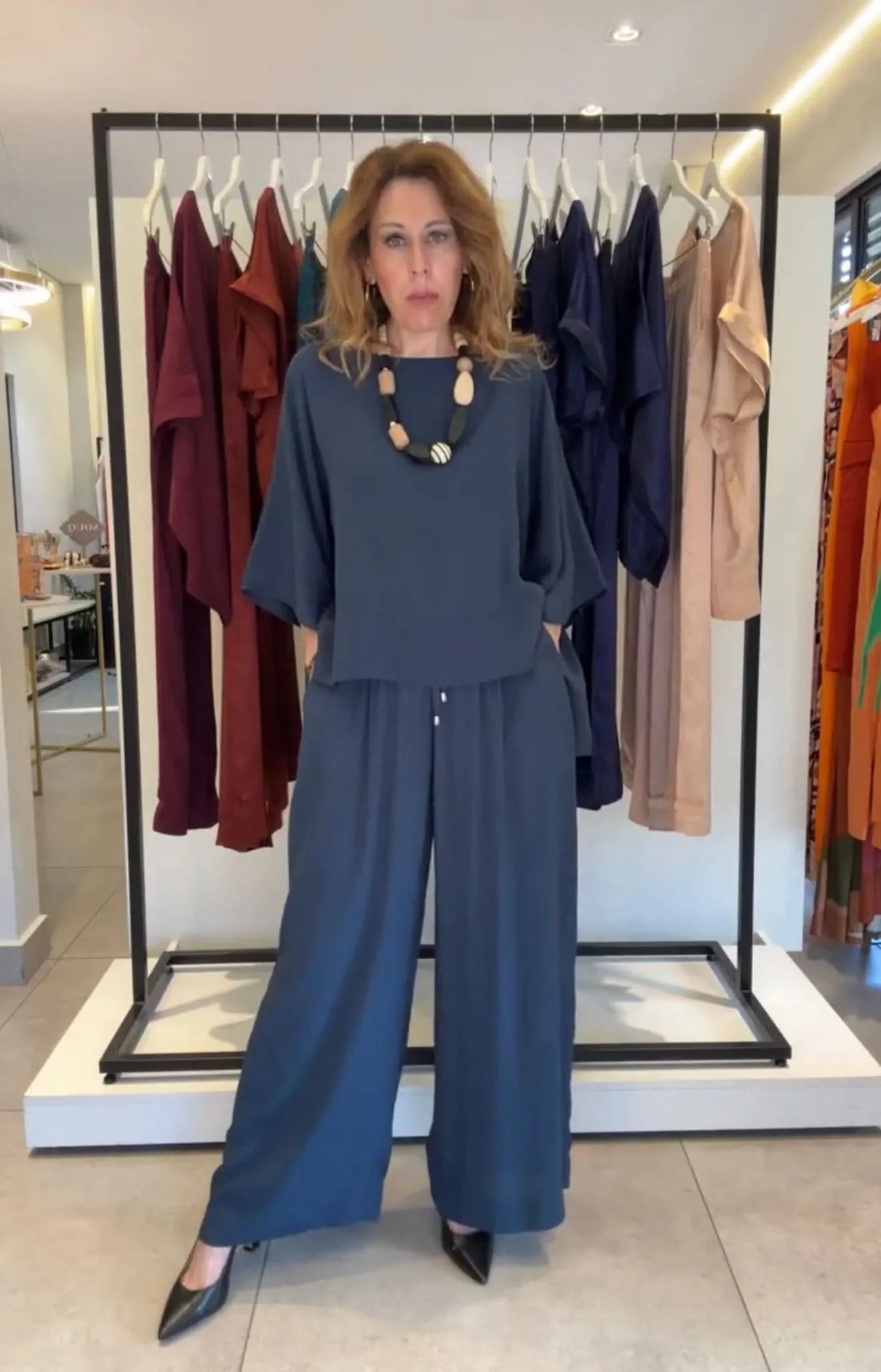 Mulher usando conjunto kimono de viscose azul, calça pantalona e colar, em loja de moda feminina EZILDINHA
