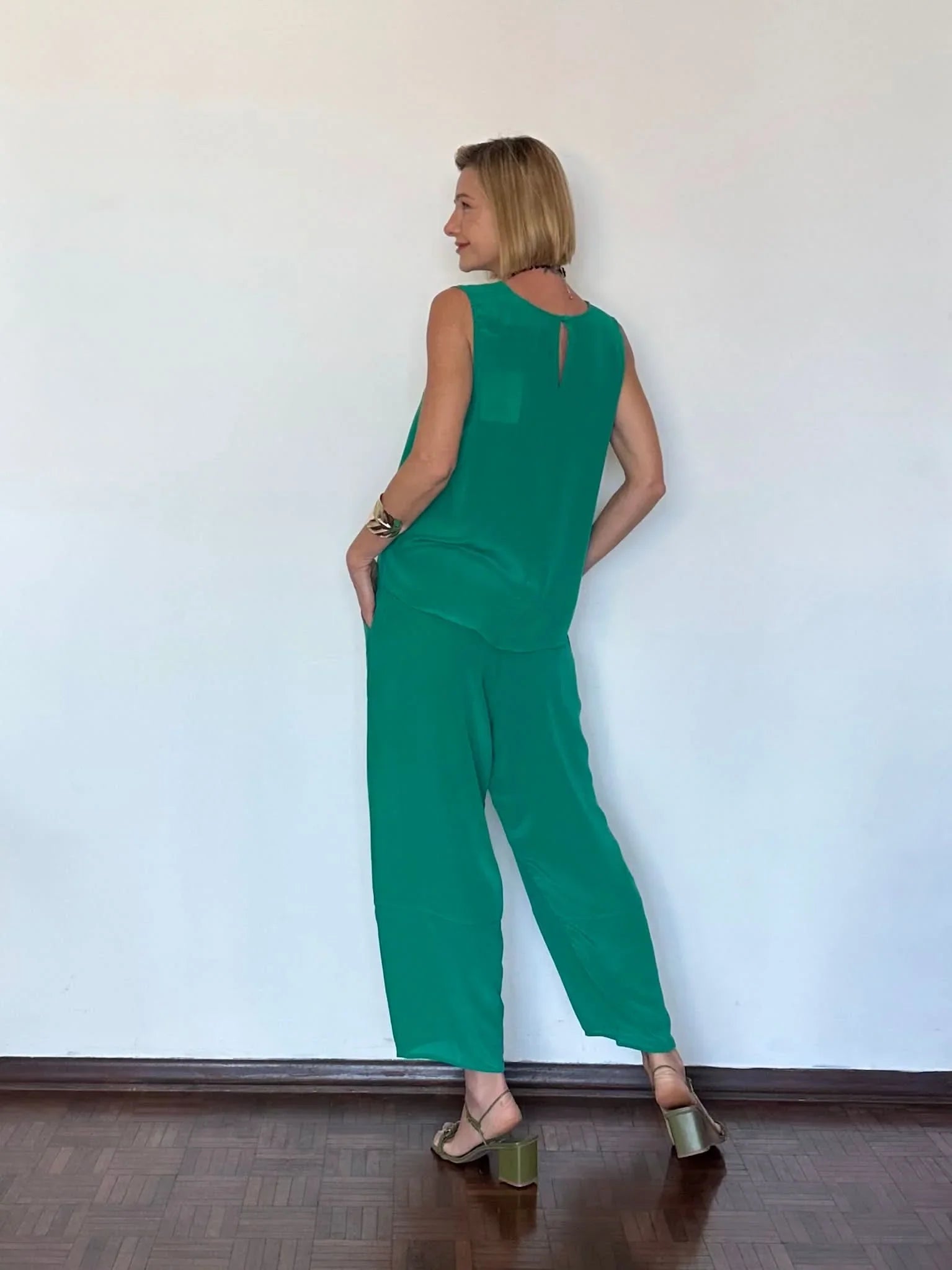 Mulher usando conjunto de seda pura verde, com blusa regata e calça pantalona elegante EZILDINHA