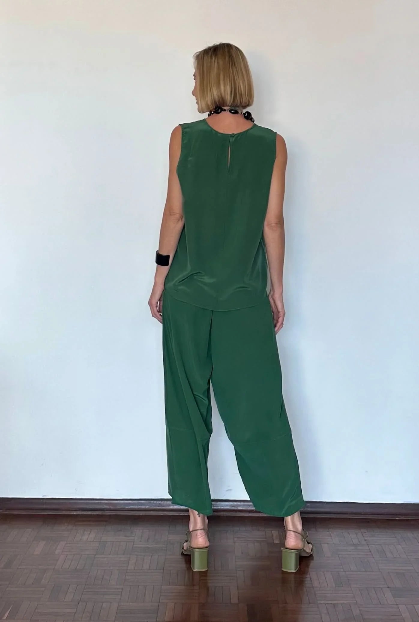 Mulher vestindo conjunto verde de seda pura, regata e calça pantalona, de costas EZILDINHA