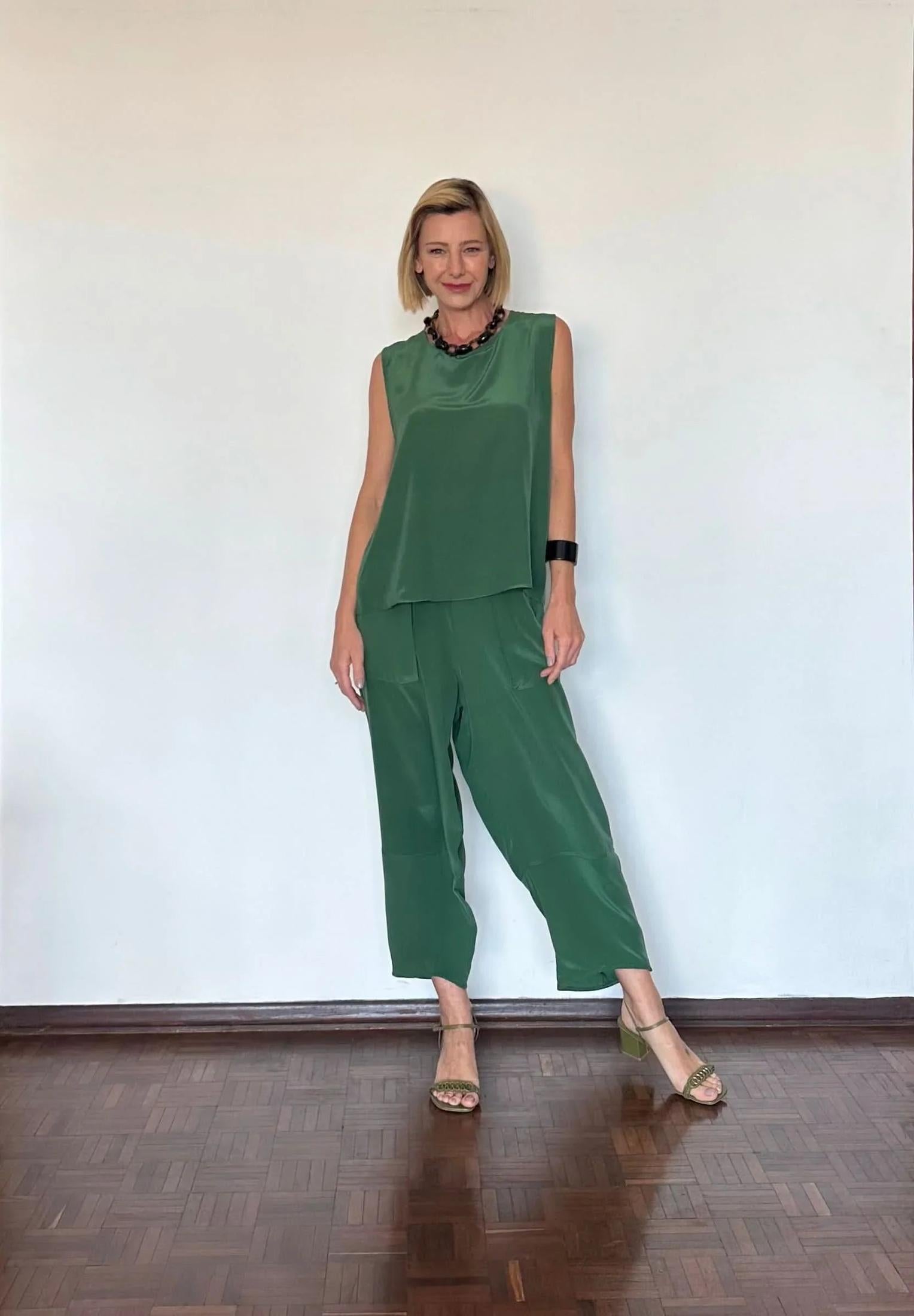 Mulher usando conjunto de seda pura verde, sem mangas e calça ampla, em ambiente interno minimalista EZILDINHA