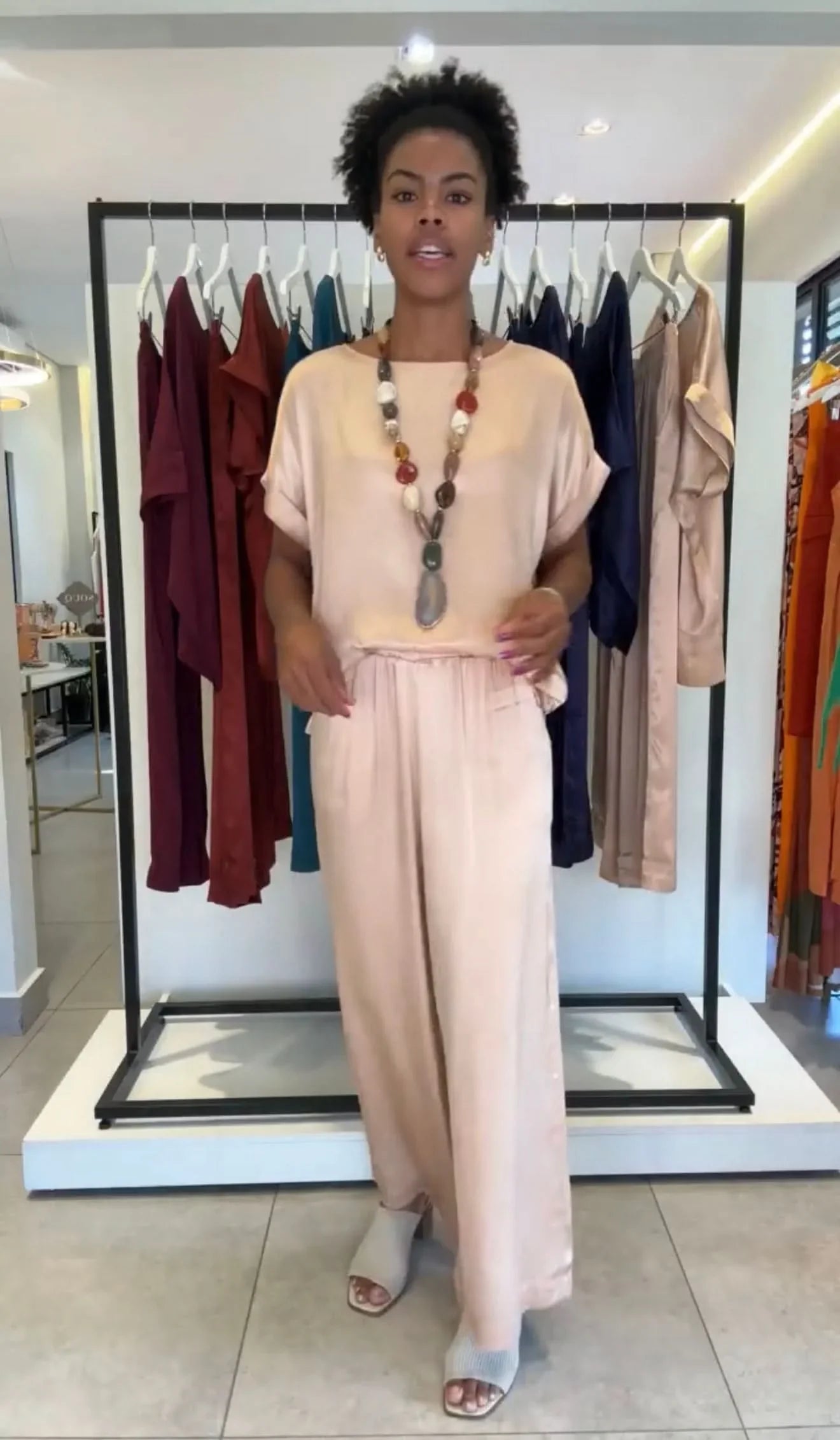 Mulher vestindo conjunto pantalona bege com manga japonesa em loja de moda feminina elegante EZILDINHA