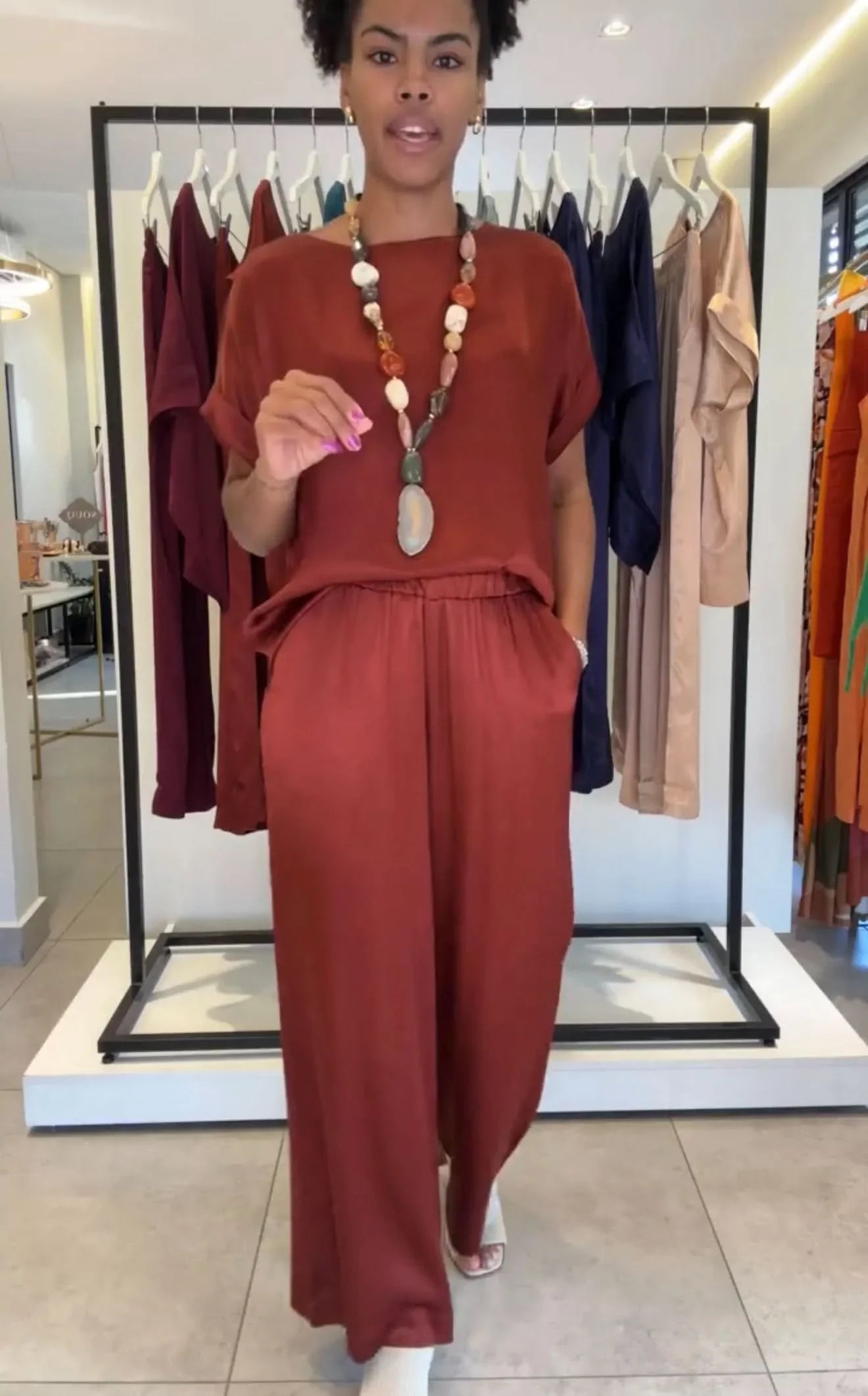 Mulher vestindo conjunto pantalona manga japonesa terracota com colar, em loja de moda feminina EZILDINHA
