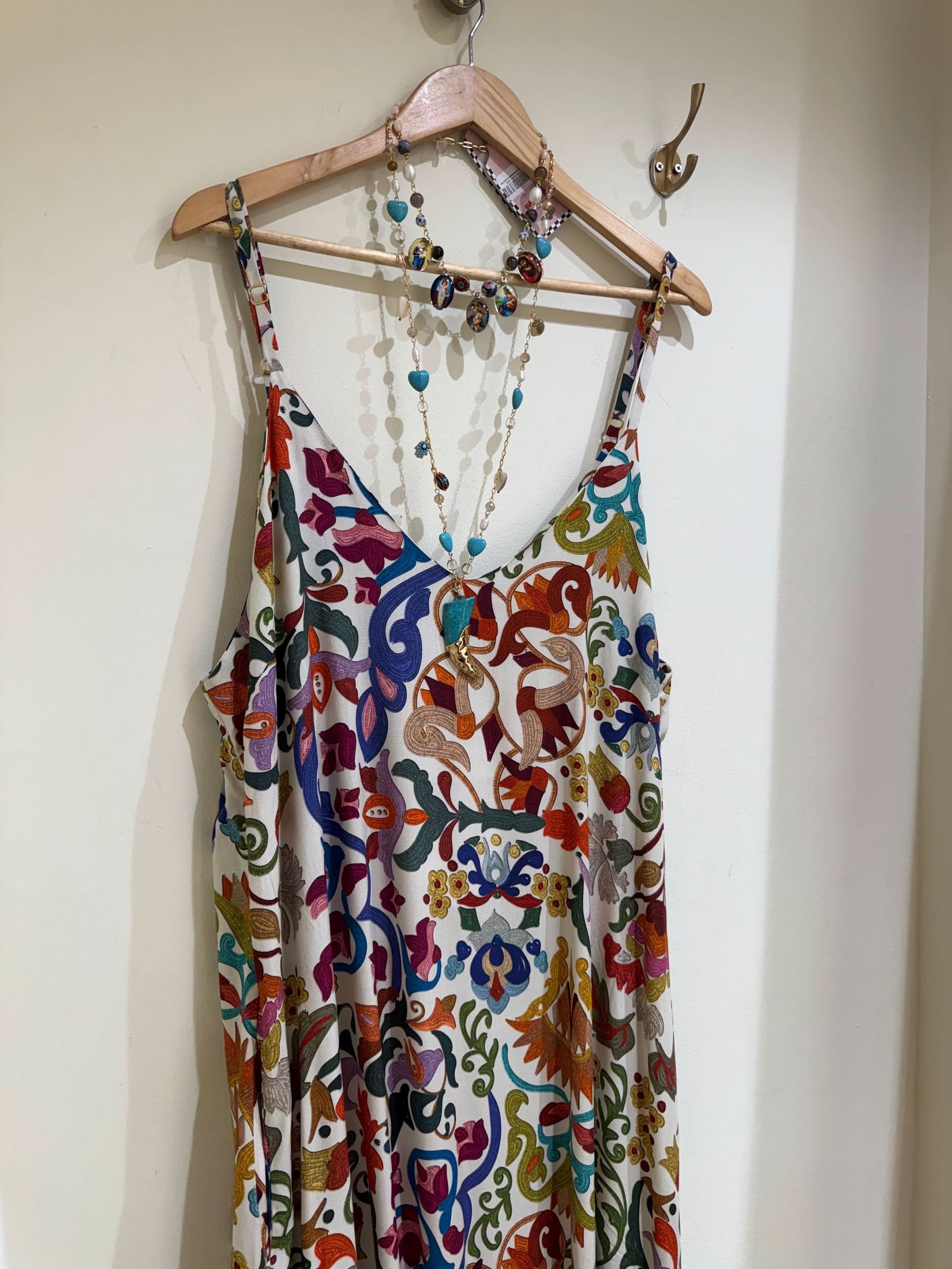 Vestido de alças estampado com padrão colorido floral e colar de pedras pendurado em cabide EZILDINHA