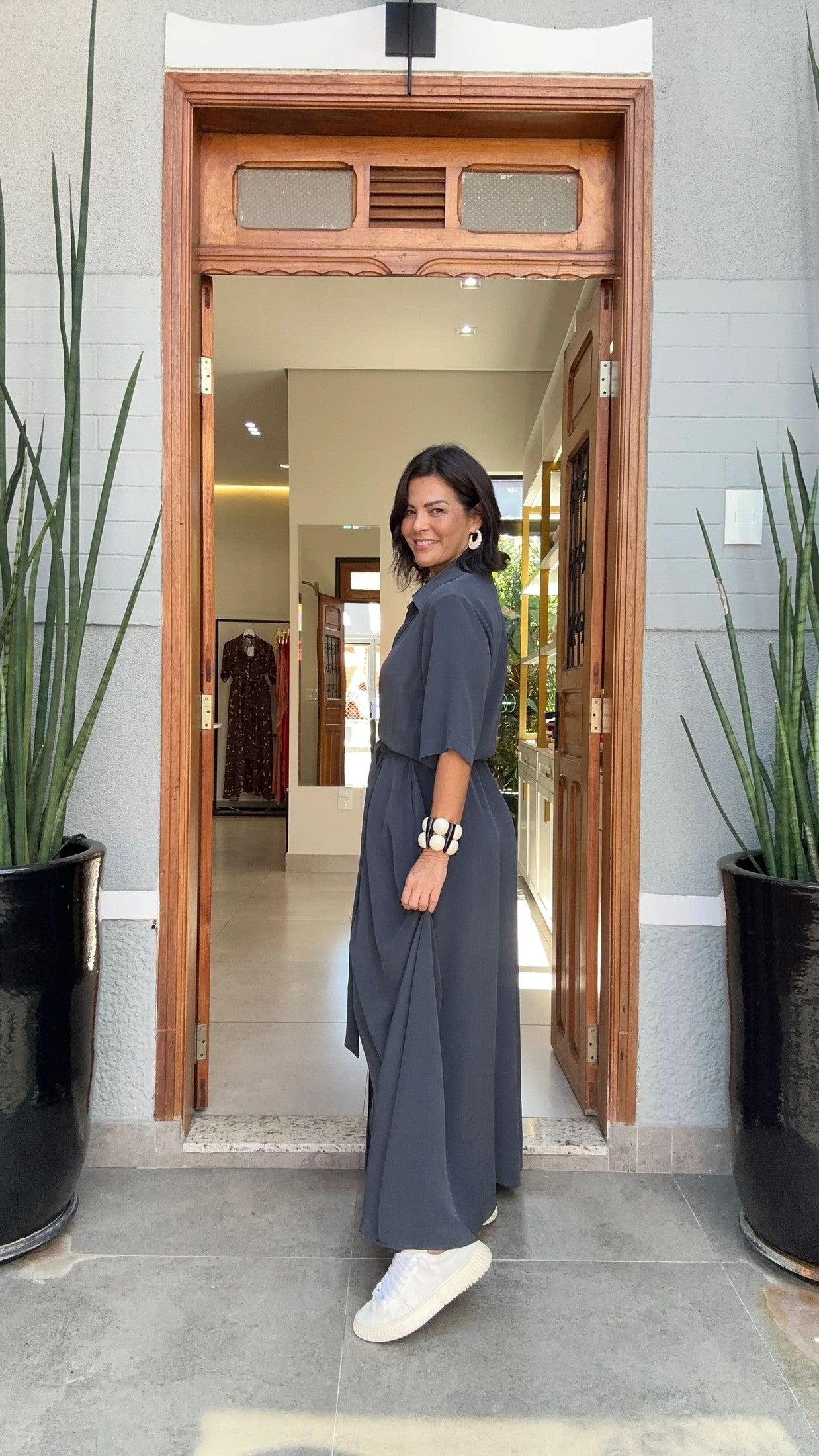 Mulher vestindo kaftan longo cinza e tênis branco em entrada elegante, moda conforto feminina EZILDINHA