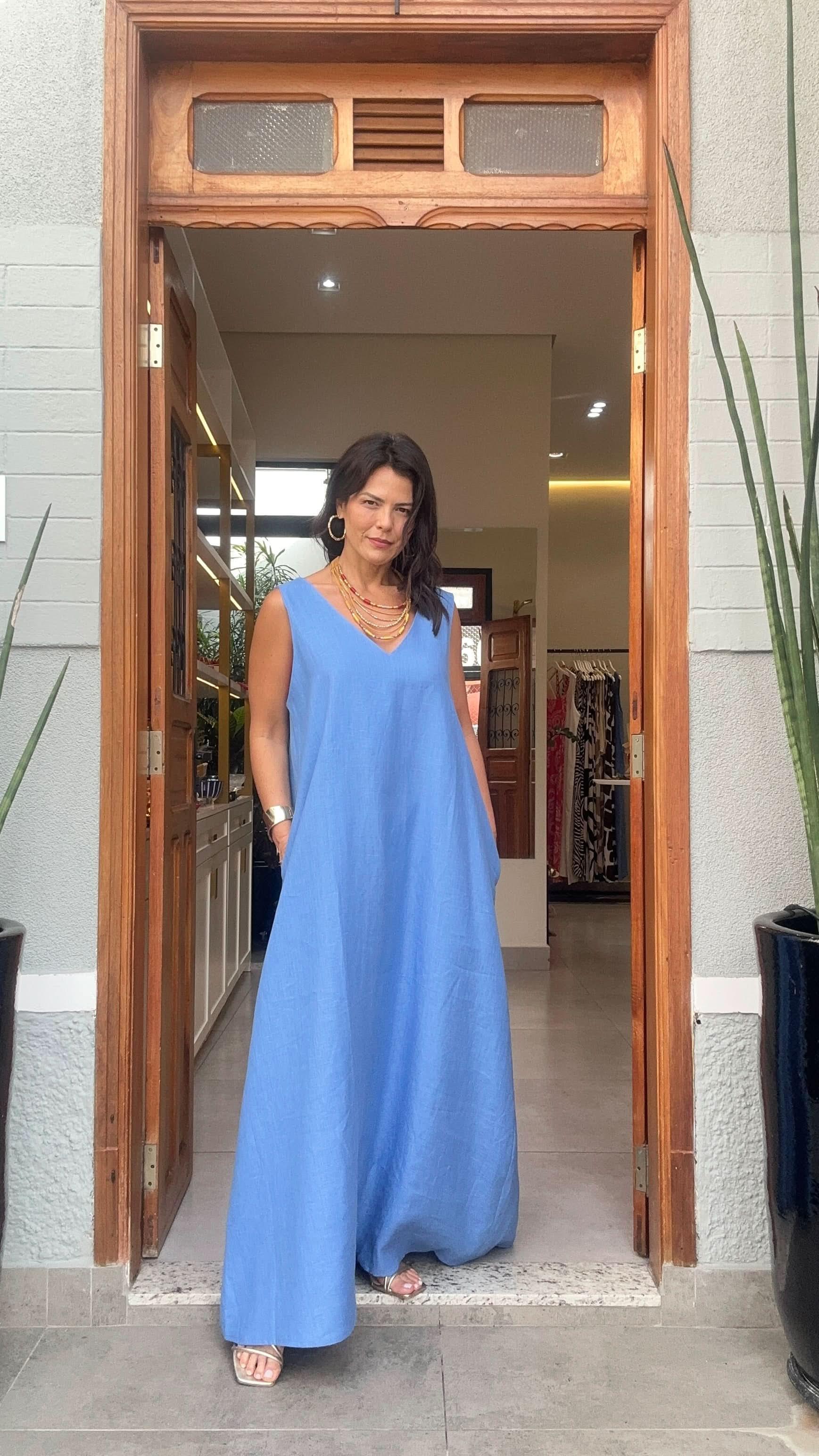 Mulher usando vestido longo de linho azul claro, na entrada de loja, moda feminina elegante EZILDINHA