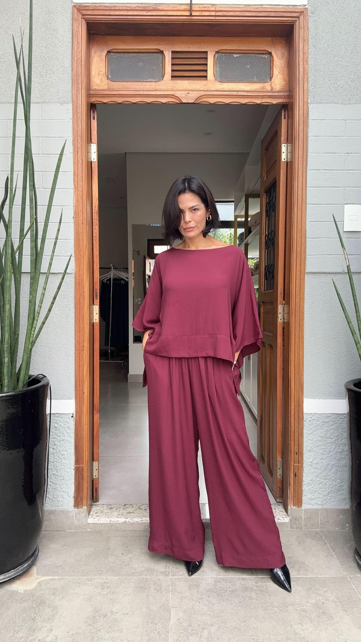 Mulher usando conjunto de blusa e calça de linho vinho, em entrada moderna, moda feminina EZILDINHA