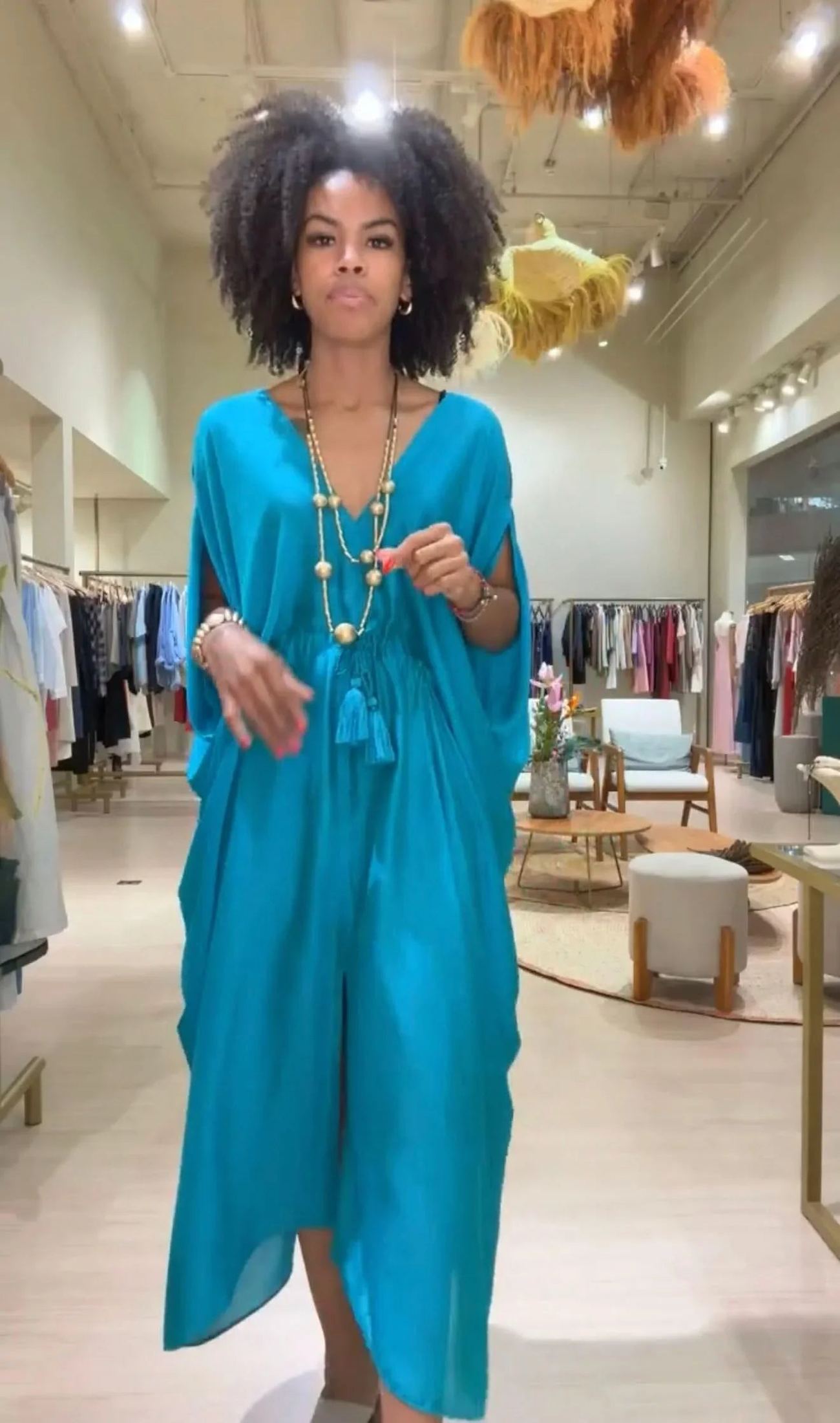 Mulher vestindo kaftan azul de seda com colar dourado em loja de vestidos elegantes EZILDINHA