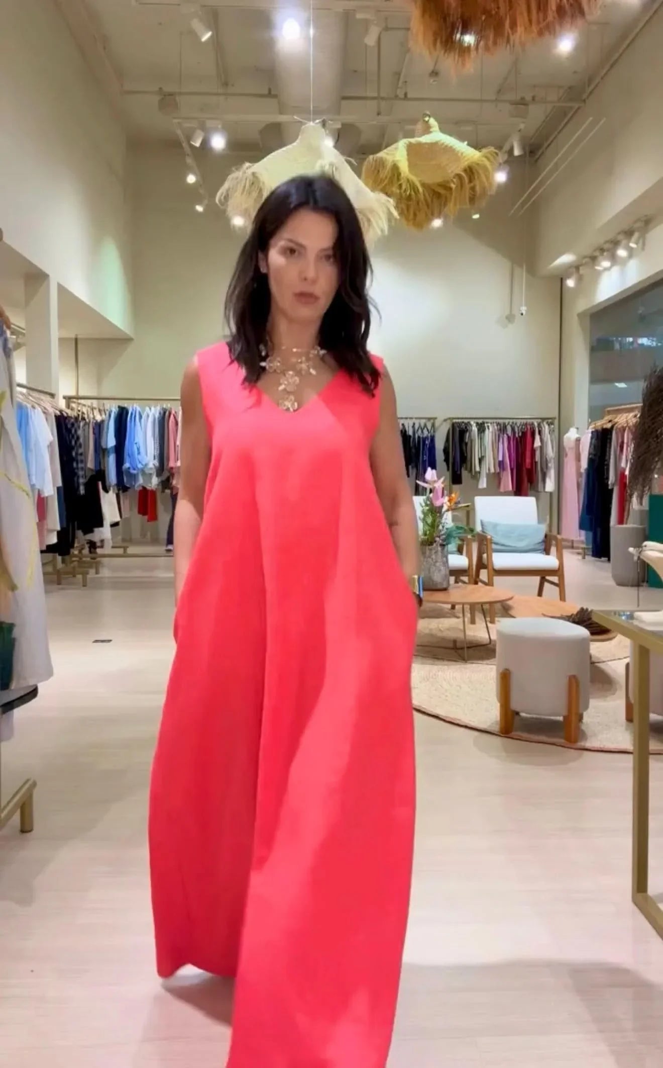 Mulher vestindo vestido longo rosa sem mangas, decote V, em loja de roupas elegante EZILDINHA