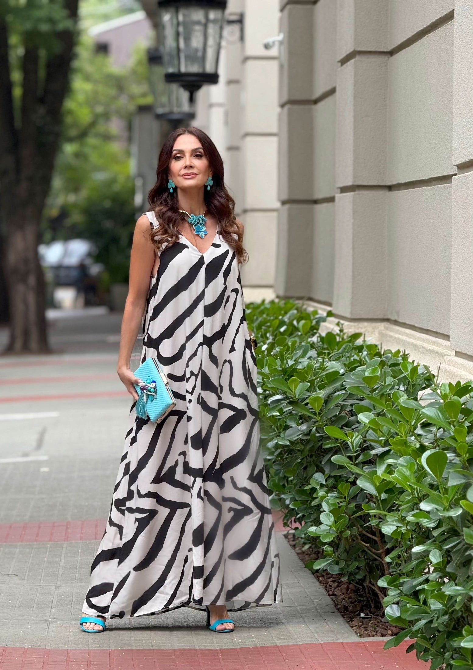 Mulher usando kaftan longo de seda com estampa preta e branca, bolsa e acessórios turquesa EZILDINHA