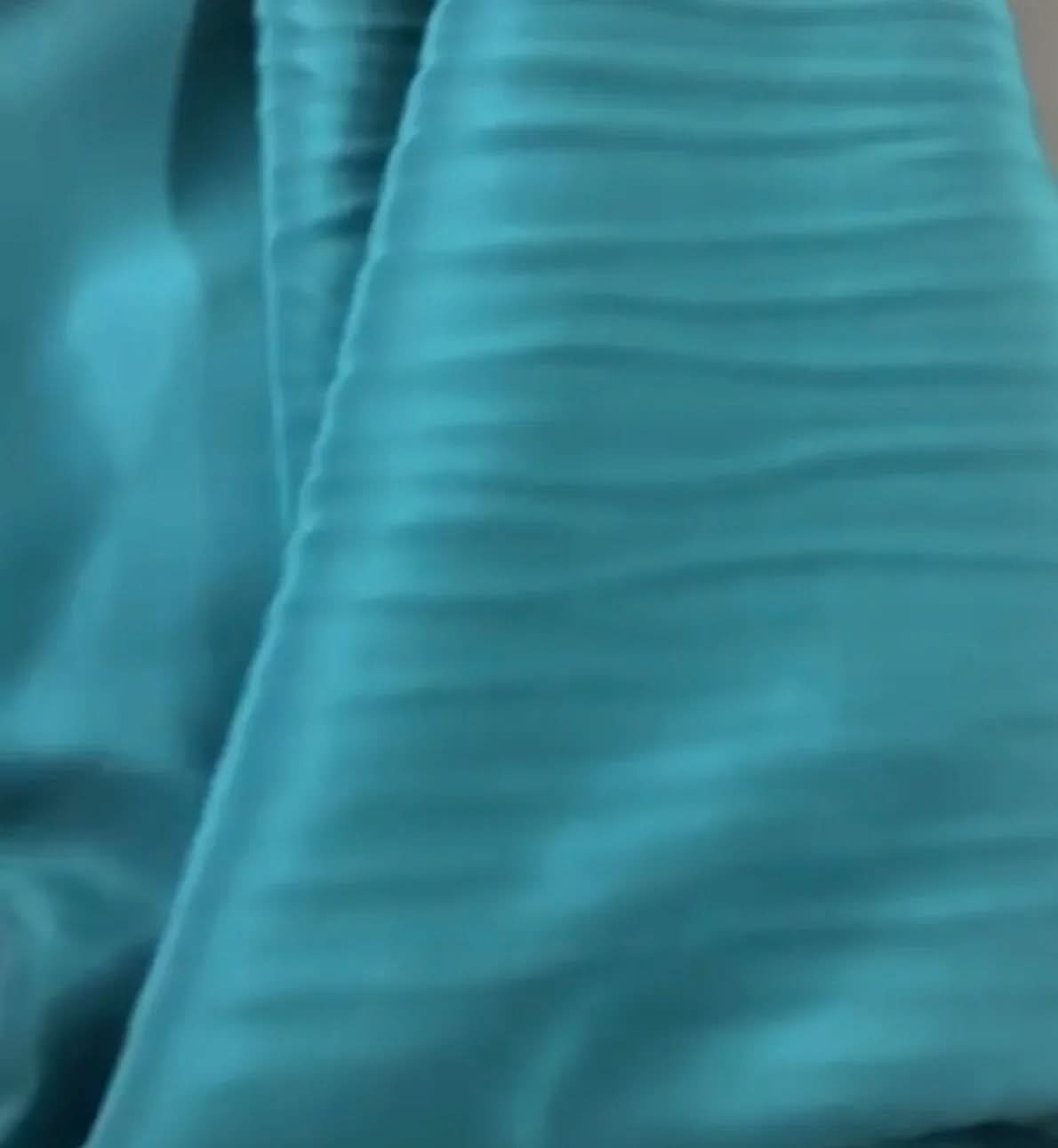 Detalhe de tecido azul claro com textura plissada em seda, ideal para vestidos ou kaftans elegantes EZILDINHA