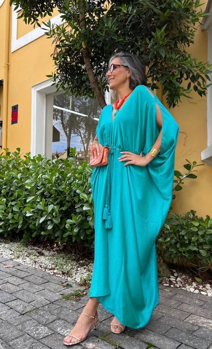 Mulher usando kaftan verde de linho com sandálias, bolsa coral e colar laranja, ao ar livre EZILDINHA
