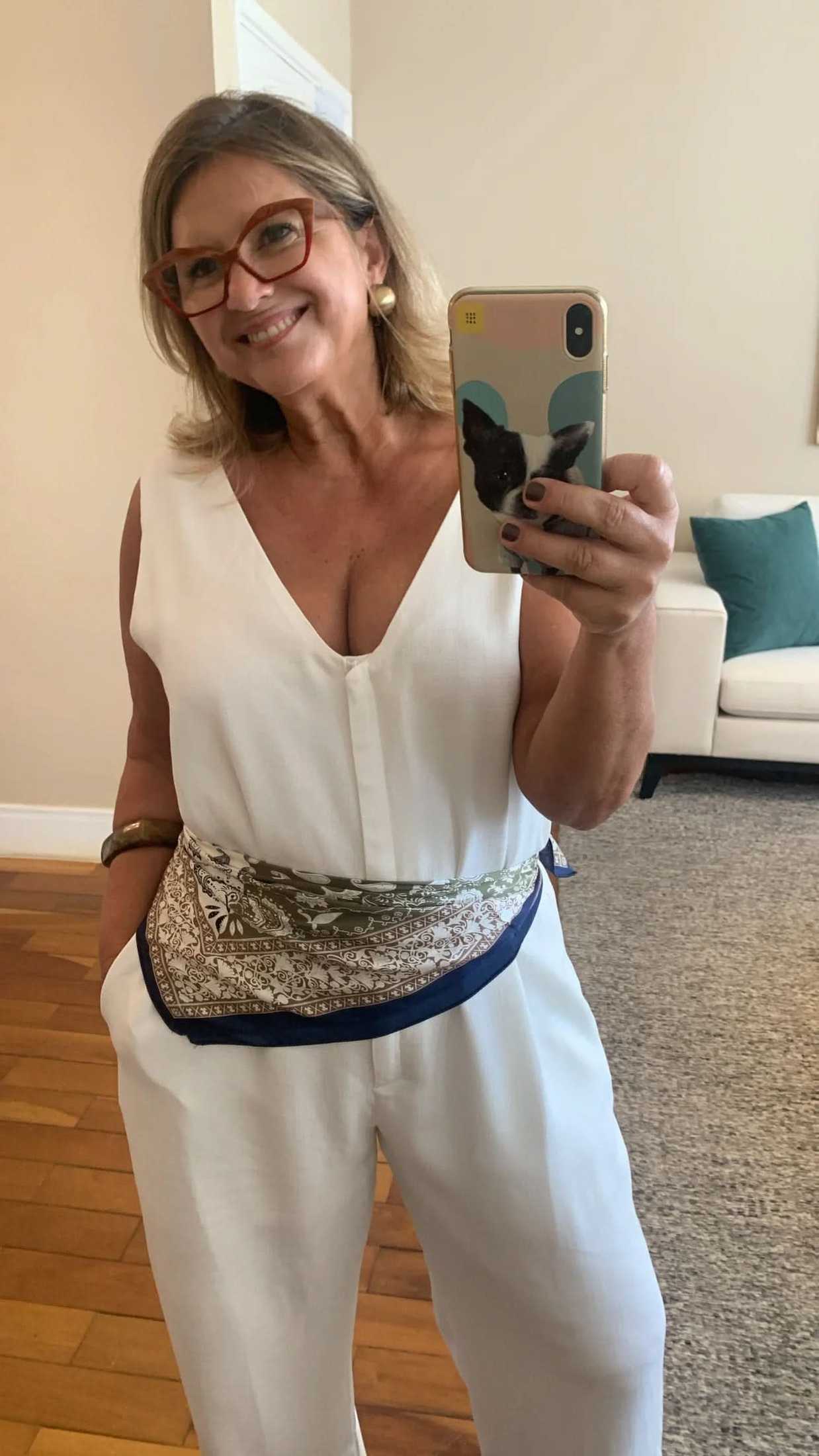 Mulher usando macacão branco de viscose com decote V e lenço estampado na cintura EZILDINHA
