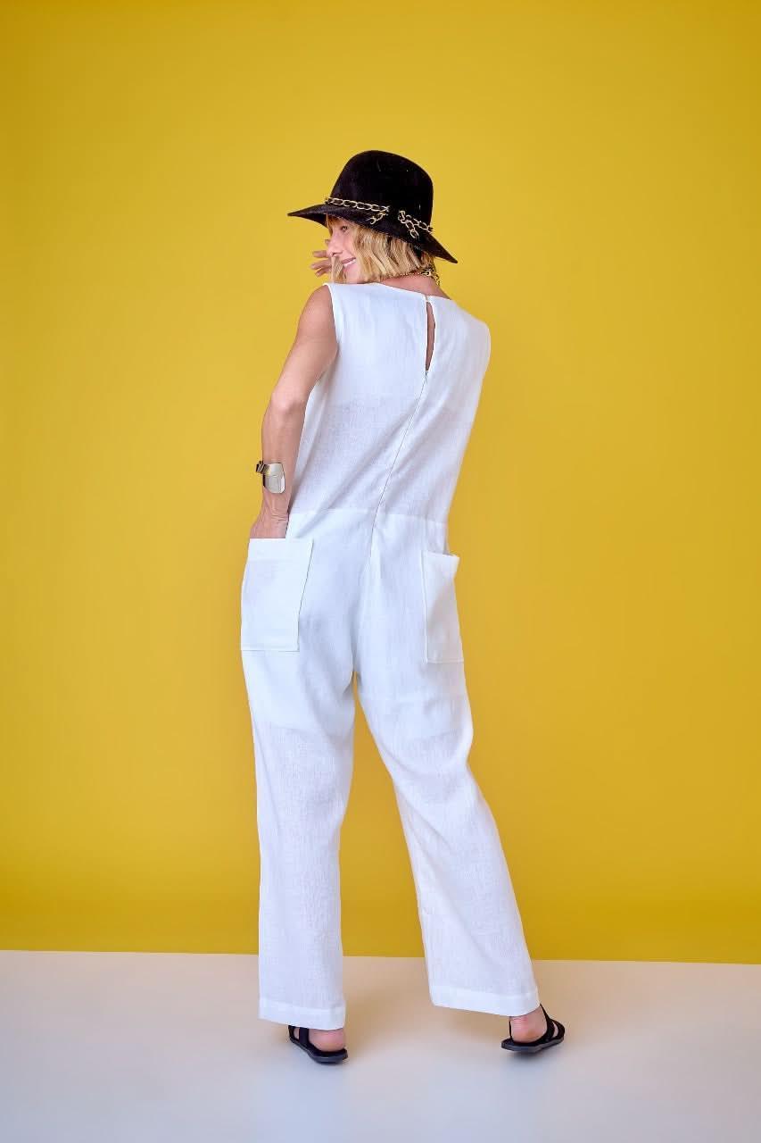 Mulher com macacão de linho branco, chapéu preto, fundo amarelo, moda elegante EZILDINHA