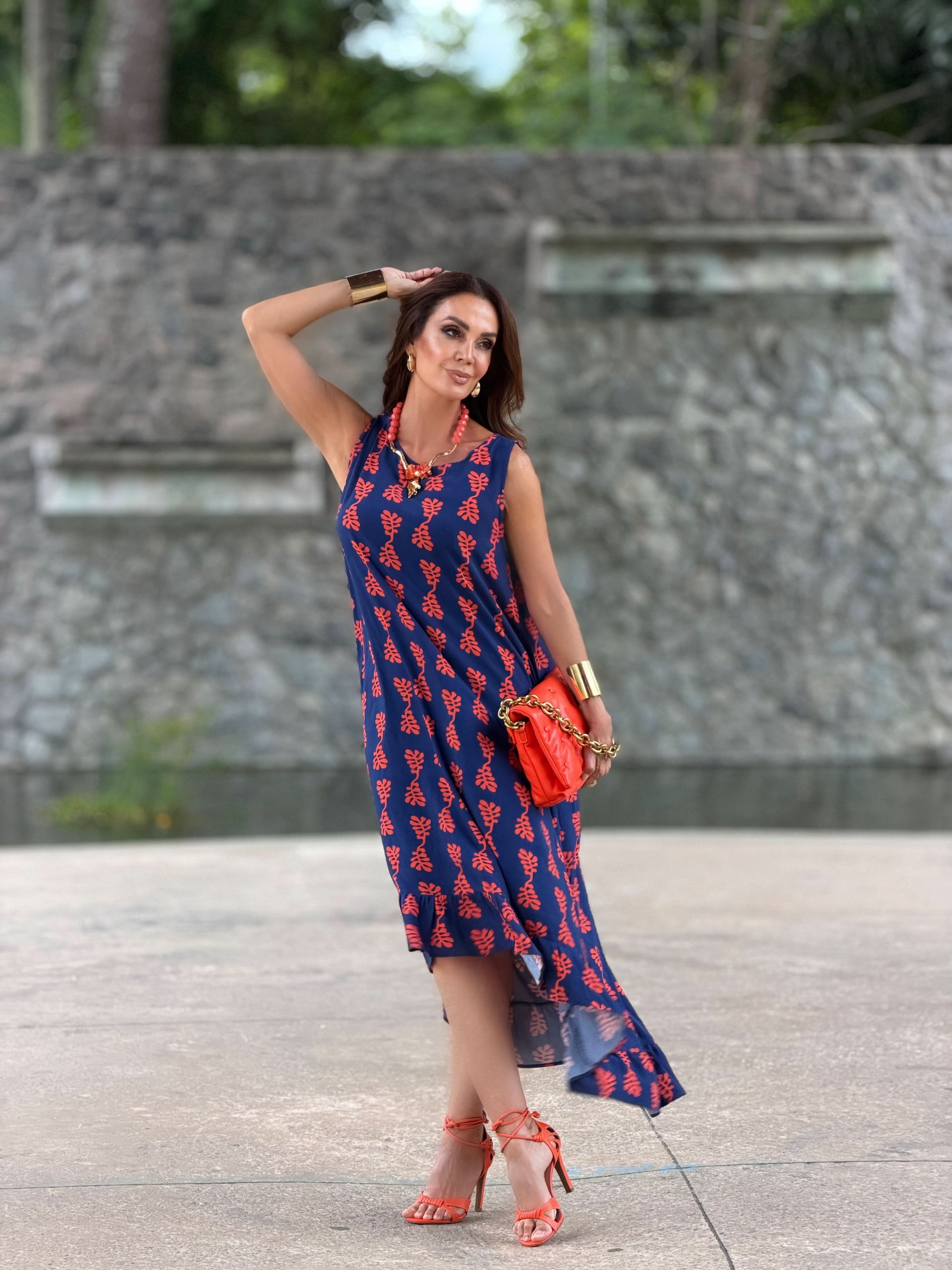 Mulher usando vestido midi azul estampado, sandálias e bolsa laranja, ao ar livre EZILDINHA