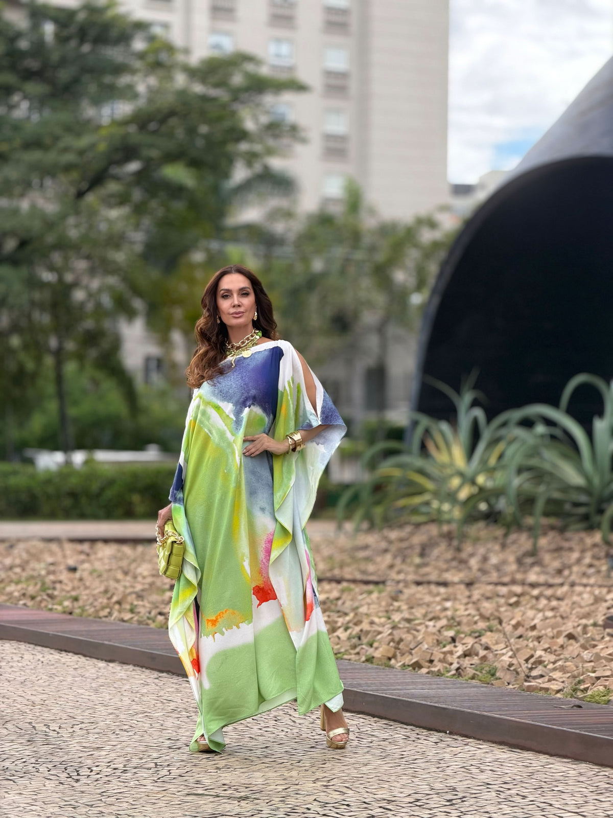 Mulher usando vestido kaftan longo estampado em tons de verde, azul e laranja, ao ar livre EZILDINHA