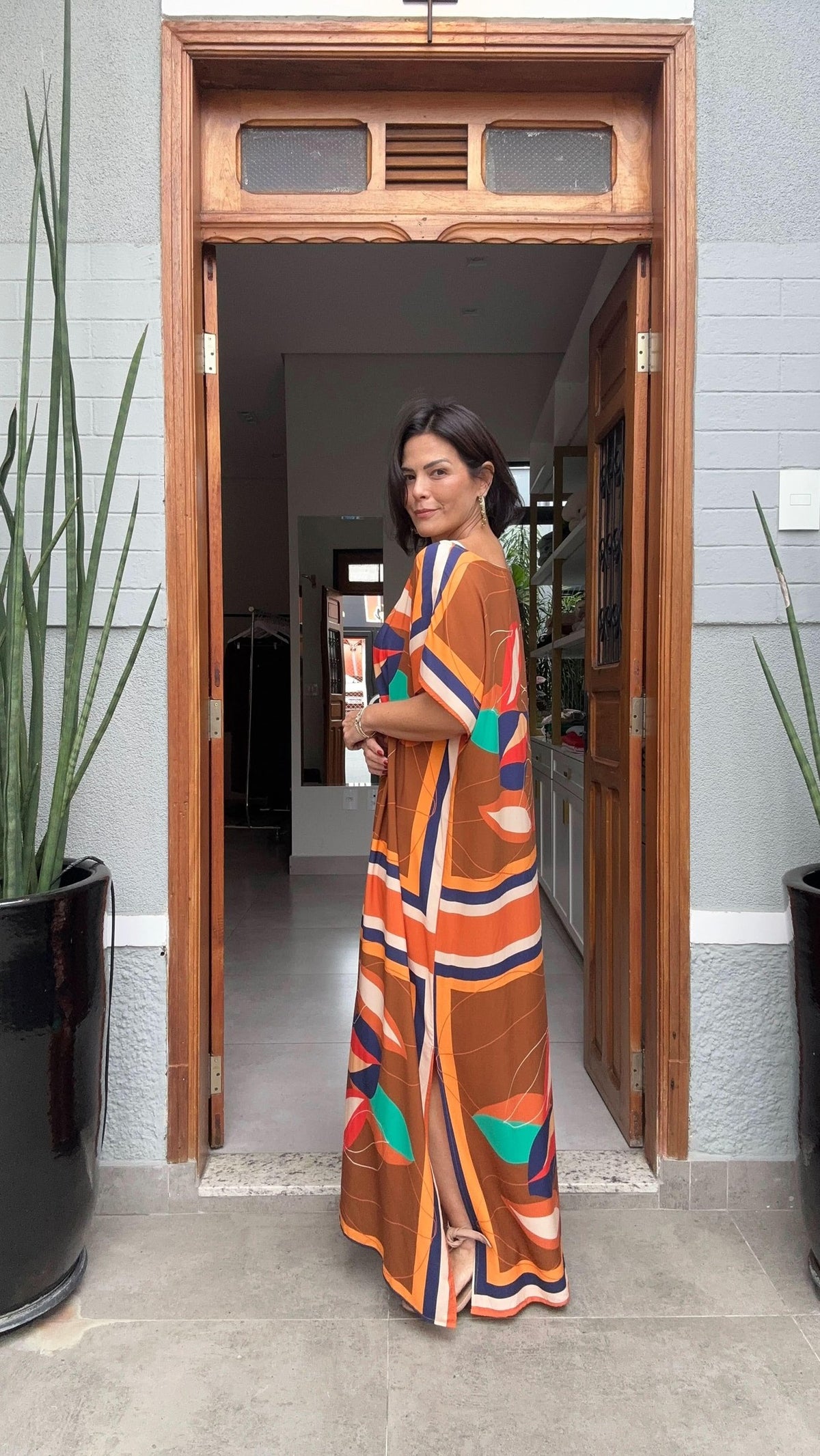 Mulher usando vestido kaftan longo estampado colorido em porta de entrada de casa moderna EZILDINHA