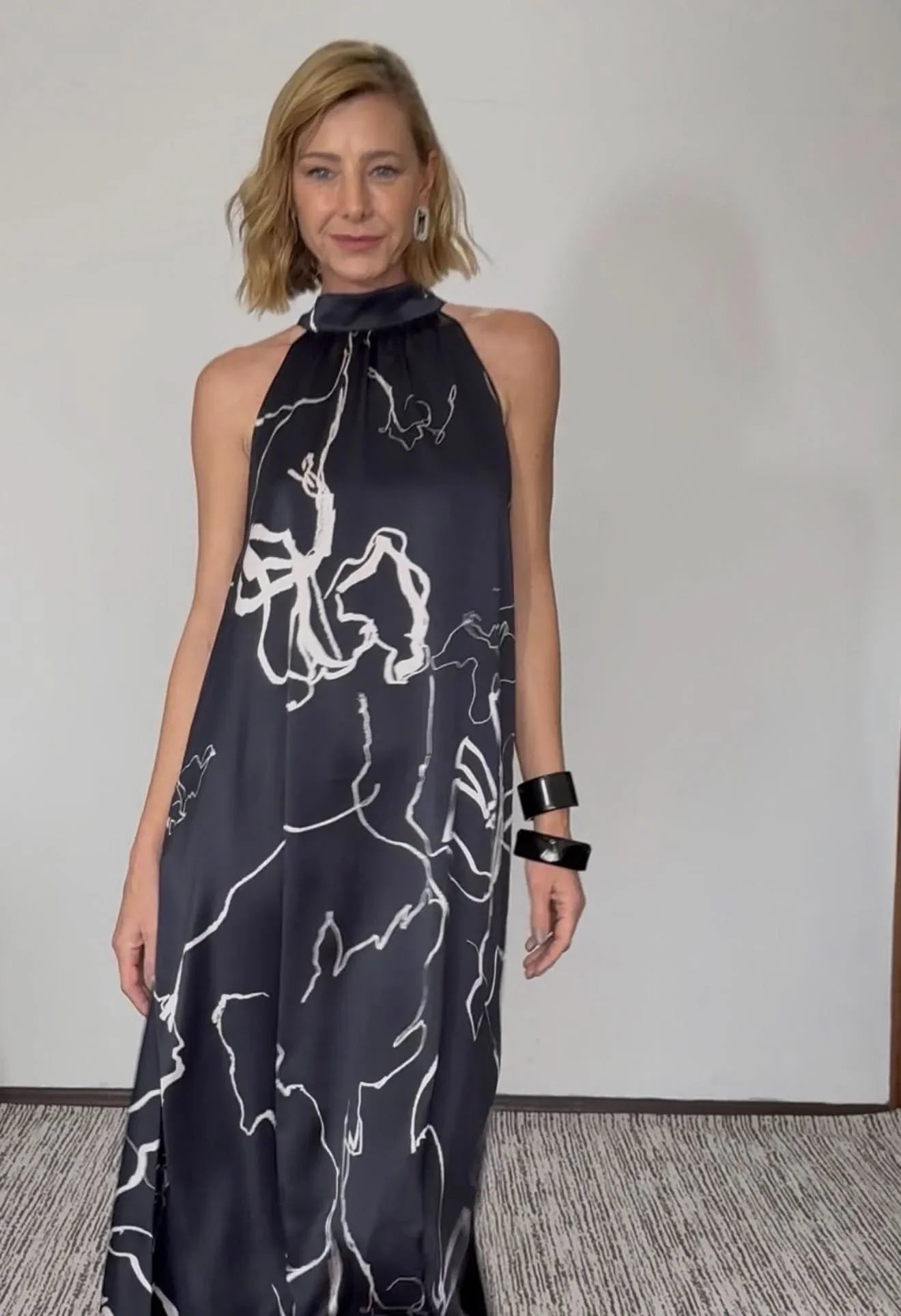 Mulher usando vestido longo de seda pura preto com estampa floral branca, gola laço EZILDINHA