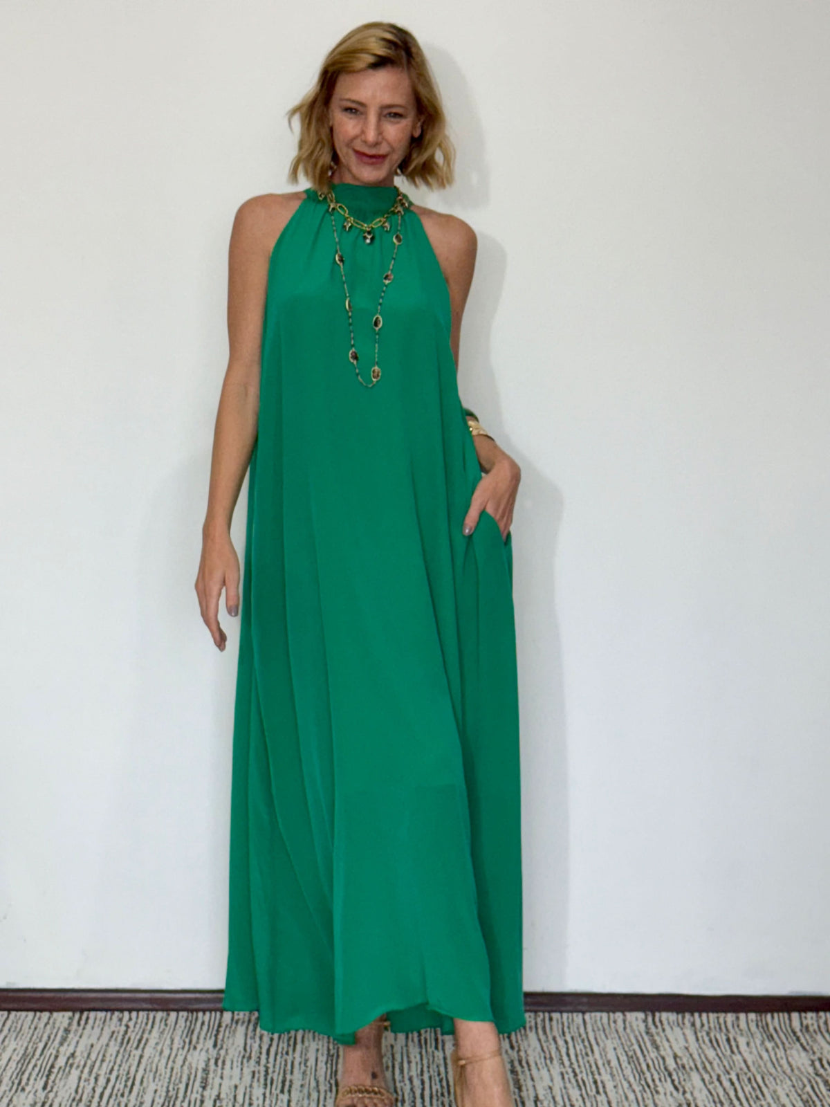 Mulher usando vestido longo verde de seda pura, modelo regata, em ambiente interno EZILDINHA