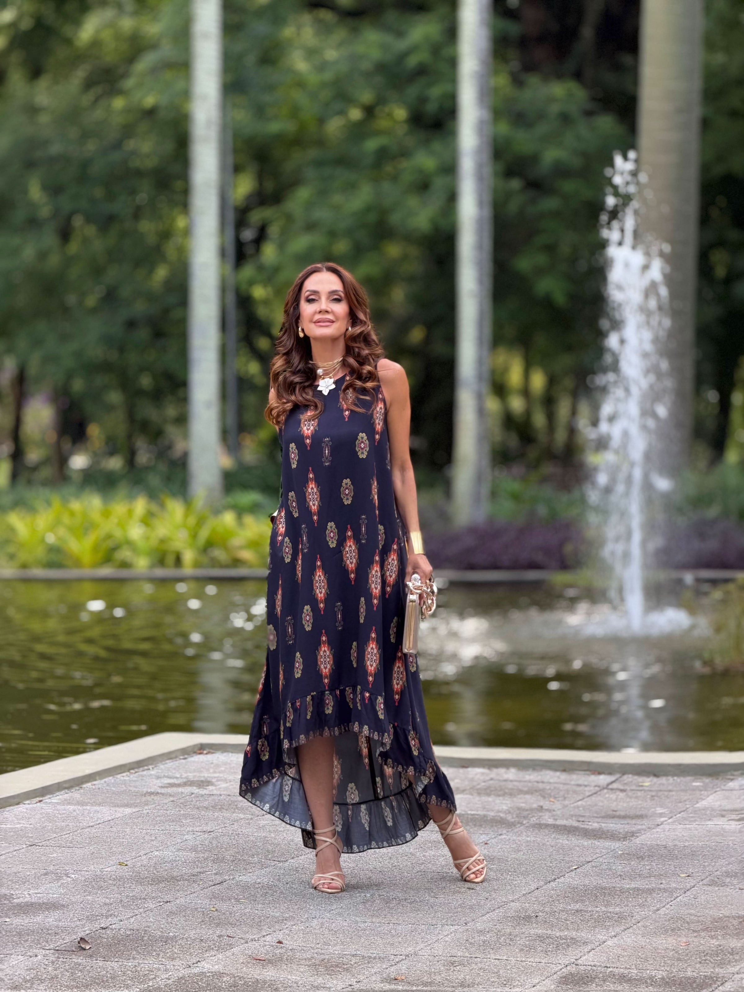 Mulher usando vestido longo de viscose estampado, elegante, ao ar livre em frente a fonte EZILDINHA