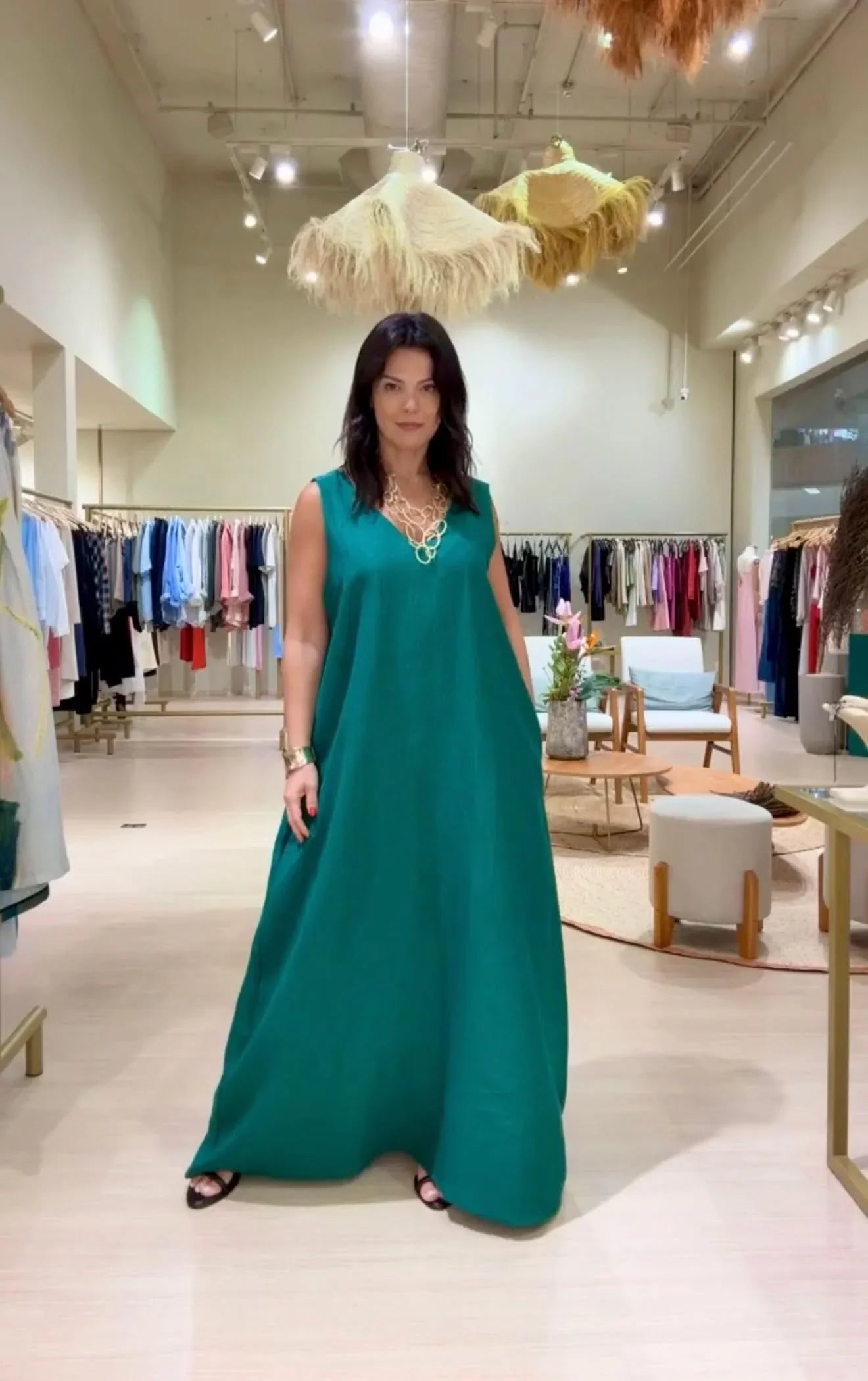 Mulher vestindo vestido longo de linho verde esmeralda em loja de roupas elegante EZILDINHA
