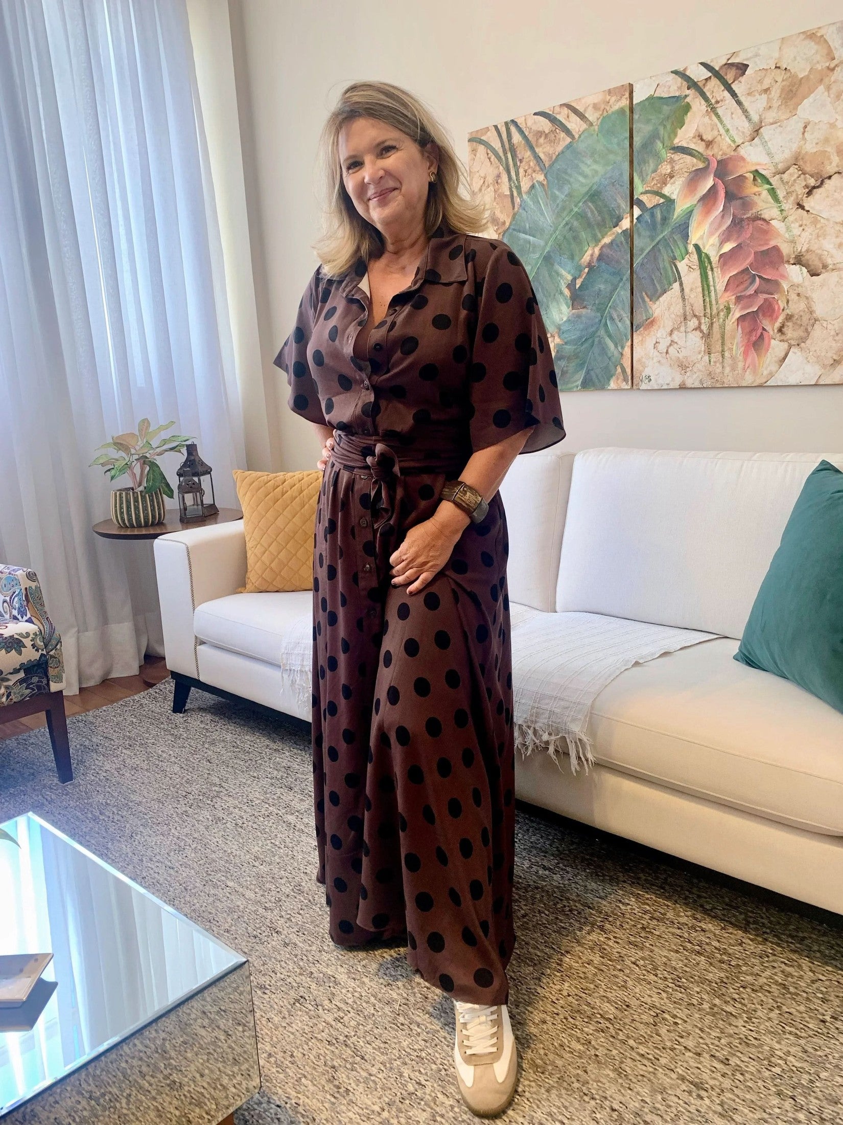 Mulher usando vestido chemisier marrom de viscose com estampa de poá, em sala de estar elegante EZILDINHA