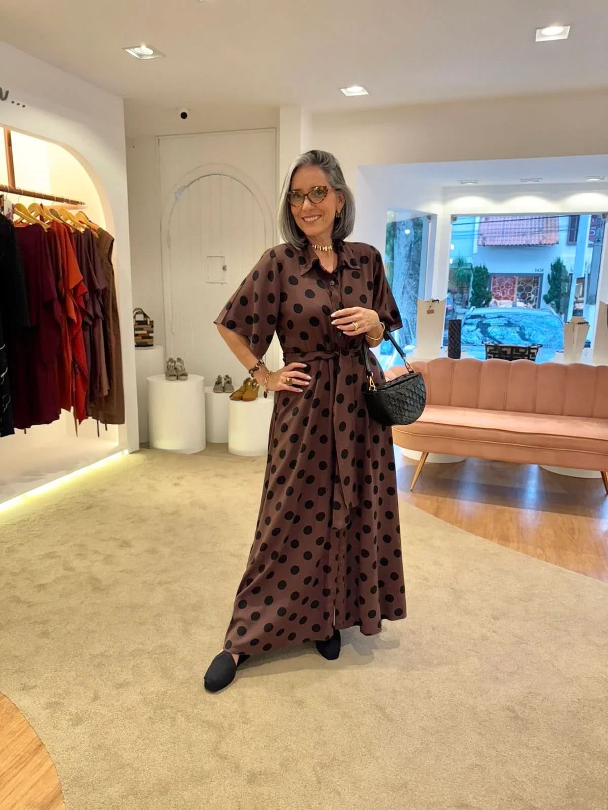 Mulher usando vestido longo marrom de poá preto em loja de moda contemporânea EZILDINHA