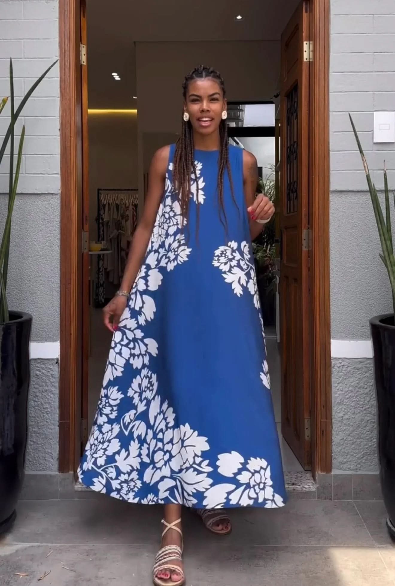 Mulher usando vestido regata azul com estampa floral branca, em entrada de loja EZILDINHA