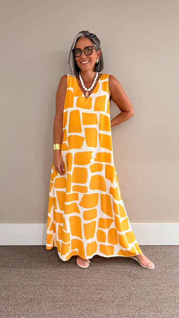 Mulher usando vestido longo estampado geométrico amarelo e branco, look elegante e casual EZILDINHA