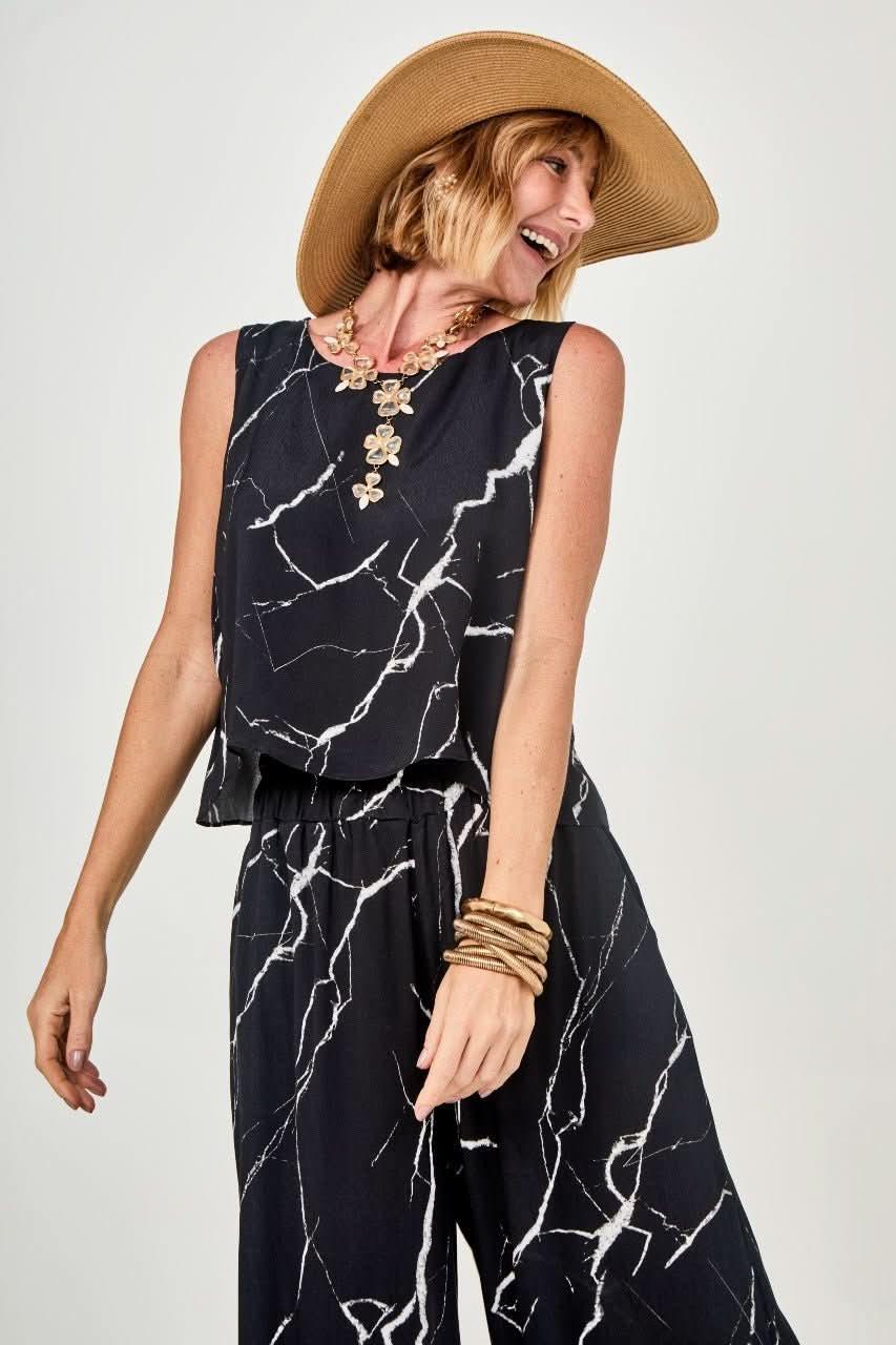 Mulher usando conjunto preto com estampa marmorizada branca, chapéu e acessórios EZILDINHA