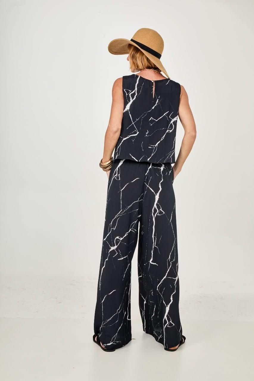 Mulher de chapéu usando conjunto preto e branco com estampa marmorizada, vista de costas EZILDINHA
