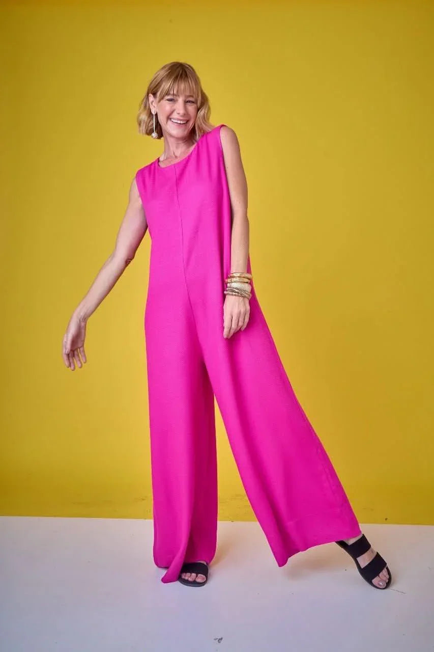 Mulher vestindo macacão pink de pernas largas, fundo amarelo, moda feminina elegante EZILDINHA