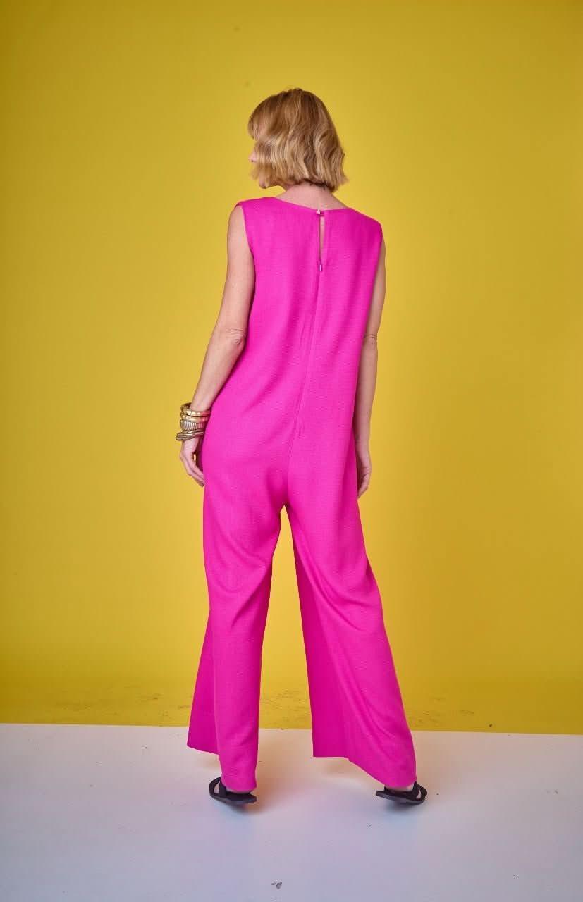 Mulher de costas vestindo macacão rosa pink sem mangas, fundo amarelo, moda feminina elegante EZILDINHA