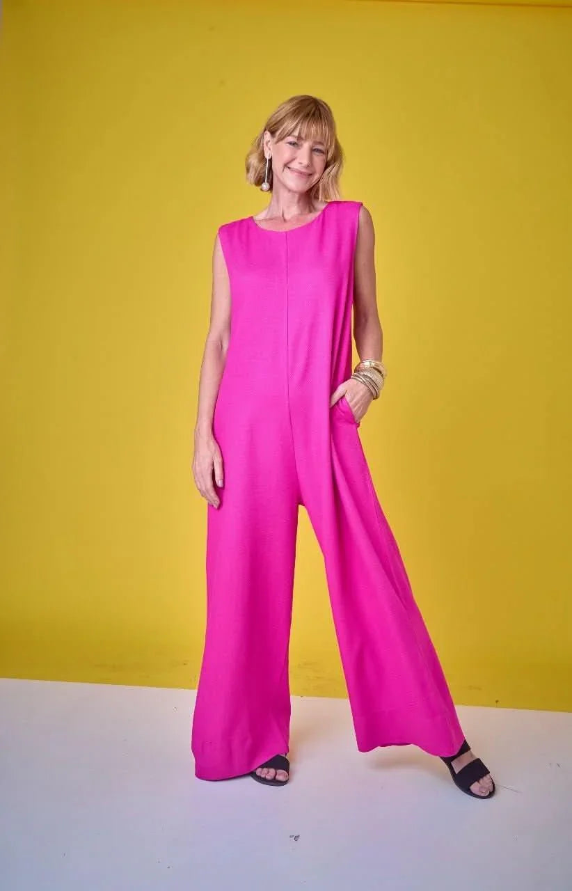 Mulher usando macacão pink de tecido leve, modelagem ampla, em fundo amarelo vibrante EZILDINHA