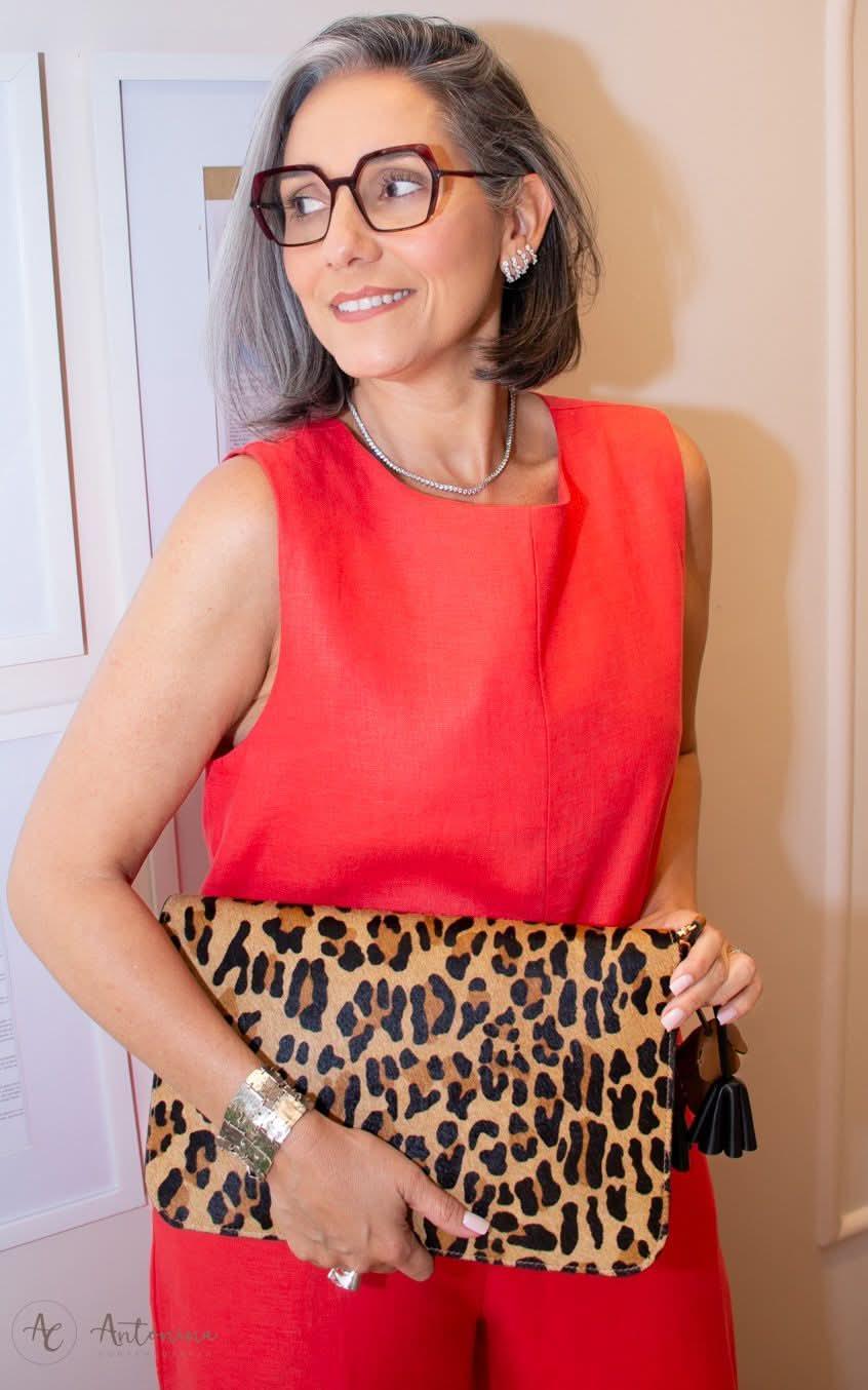 Mulher elegante com macacão de linho vermelho e clutch animal print na mão EZILDINHA