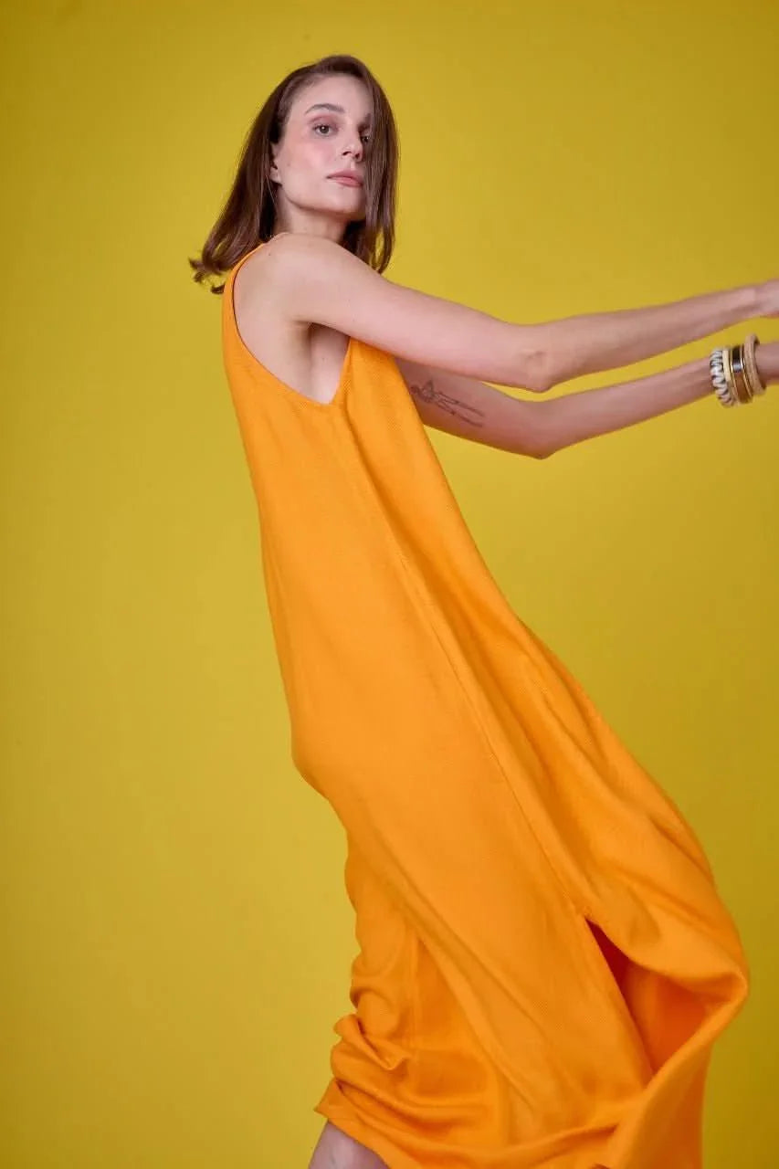 Mulher usando vestido longo amarelo mostarda em fundo amarelo, moda feminina elegante EZILDINHA