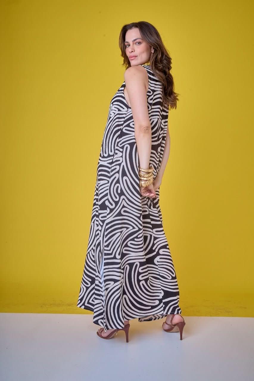 Mulher usando vestido longo preto e branco estampado com linhas, fundo amarelo EZILDINHA