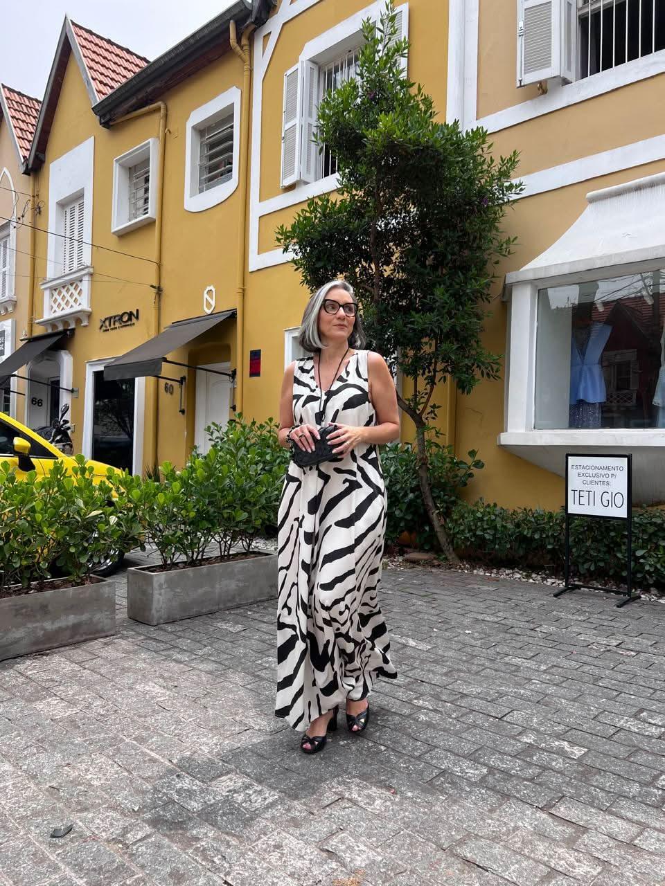 Mulher usando vestido longo de pregas com estampa abstrata preta e branca ao ar livre EZILDINHA